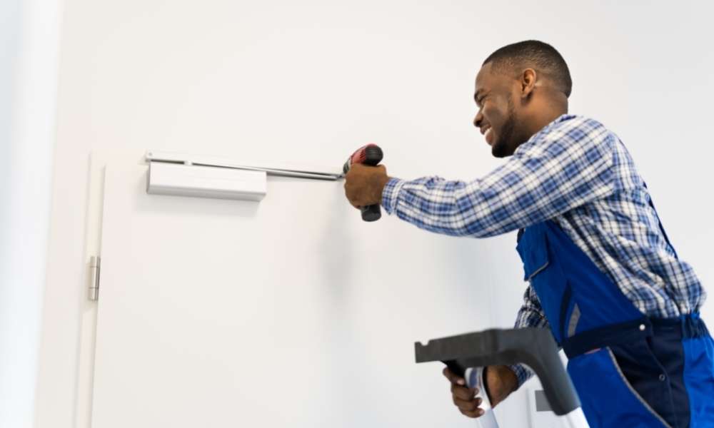 A professional adjusting a door closer